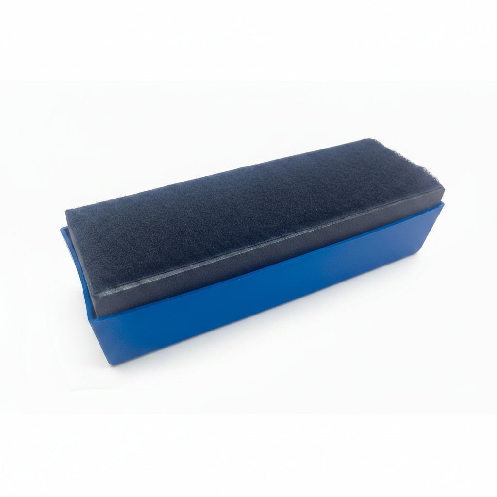 A rectangular blue plastic brush holder or case with a dark charcoal gray textured brush or felt pad on top, shown on a plain white background.